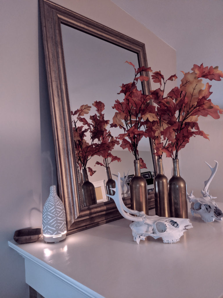 diffuser, mirror, fall leaves in gold vases, and deer skulls on mantle